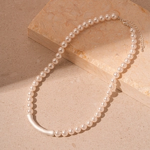 Vintage pearl necklace with a curved silver tube and lobster clasp on marble stone