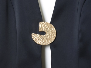 Détail de la boucle en métal martelé doré sur une mini robe noire design