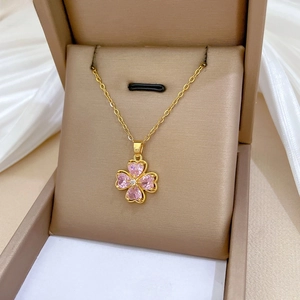 Detailed shot of a gold clover necklace with pink heart crystals in a gift box