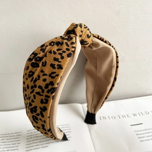 Detail of yellow leopard print knotted headband on a vintage book with stylish textures