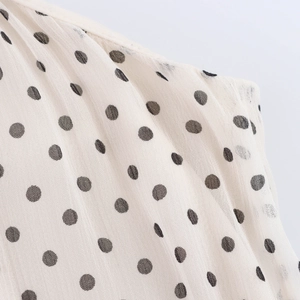 Elegant white polka dot halter maxi dress with flowing fabric and large hem detail
