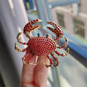 Macro shot of a luxury red rhinestone crab brooch with blue crystal eyes in natural light