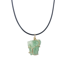 Detail of green raw stone pendant wrapped in handmade gold wire on a black cord