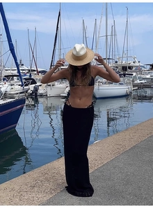 Lifestyle shot of a woman wearing a two-tone wide brim raffia straw hat by the marina