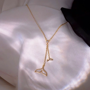 Elegant gold fishtail tassel necklace with shell inlay and zircon on white satin cloth