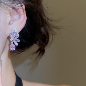 Close-up of pink teardrop zircon earring with silver butterfly wing in high polish finish