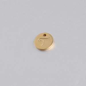 Vista macro di un ciondolo circolare d'oro in acciaio inox con lettera T incisa