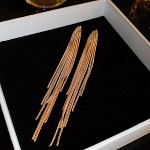 Detailed macro shot of elegant long gold tassel earrings on a premium black velvet lining