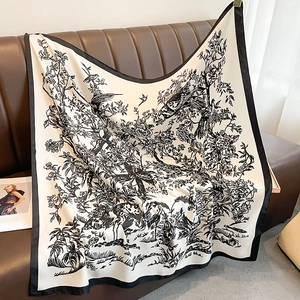 Dettaglio dell'elegante stampa di fiori e uccelli su foulard in seta posato sul divano