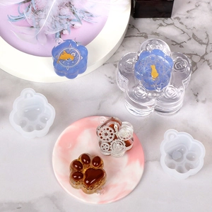 Macro detail of transparent silicone cat paw molds and resin craft samples on marble base