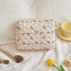 Detail of quilted cream makeup bag featuring cartoon elephant motifs and soft texture