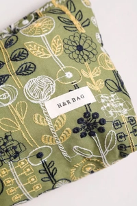 Close-up of floral embroidery on linen cosmetic bag with H&R BAG woven label