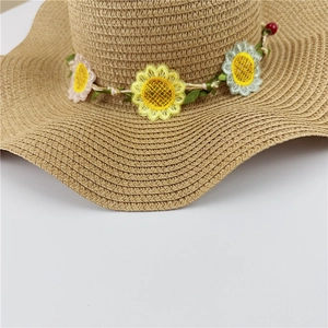 Détail d'un chapeau de paille orné de broderies de tournesols et de bords ondulés