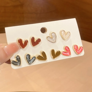 Close-up of five pairs of heart-shaped colorful enamel earrings on a display card