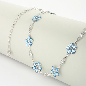 Detailed close-up of a silver chain belt with blue floral crystals on a grey prop