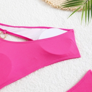 Detail of rose red ribbed bikini featuring a gold metal ring and premium textured fabric