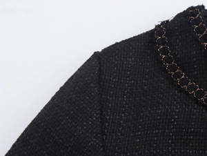 Dettaglio del tessuto in tweed nero con raffinati ricami in metallo dorato lucido