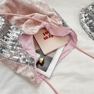 Top view of sequin tote bag filled with magazines and cosmetics on a soft white bed