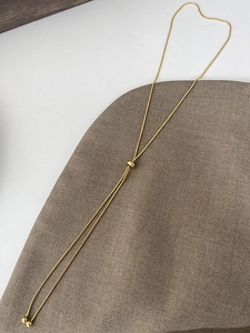 Close-up of golden snake chain Y-necklace with sliding adjustment buckle and beads