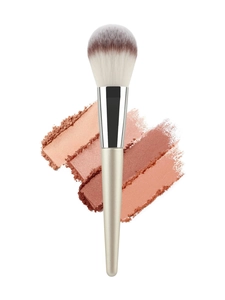 Close-up of champagne makeup brush with bicolored bristles over colorful cosmetic powder smears