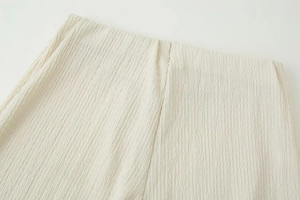 Detail of white crinkle fabric texture and waist stitching on straight leg pants