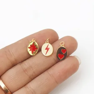 Macro detail of red enamel gold charms including star, lightning, and heart shapes