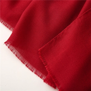 Primer plano detallado del suave tejido rojo y los flecos finos de este pañuelo largo