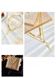 Detail of double-layer gold star and bar pendant necklace on a beige stone surface
