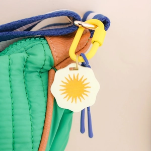 Sac matelassé vert avec bordure en cuir marron et pendentif fleur de soleil jaune