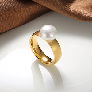 Detail of a pearl gold ring with a brushed stainless steel wide band on silk background