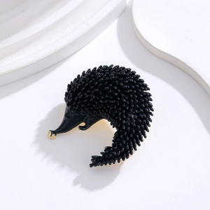 Detailed close-up of a black enamel hedgehog brooch with a gold-tone nose and metal finish