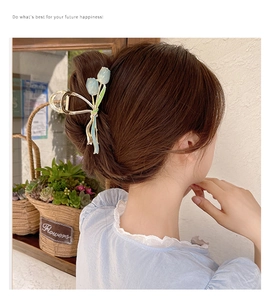 Close-up of a light blue tulip hair claw clip worn on a messy bun with golden metal finish