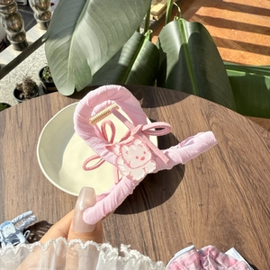 Close-up of pink fabric hair claw clip with cat character and bow held by hand