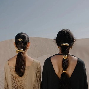 Golden stainless steel bow and star hair ties shown against a desert backdrop