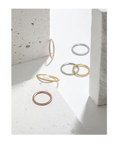 Three dainty eternity rings in gold, silver and rose gold on a minimalist stone display