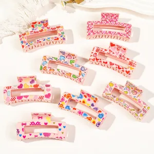 Close-up of 8 pink hair claw clips with love heart patterns and stylish doodle prints