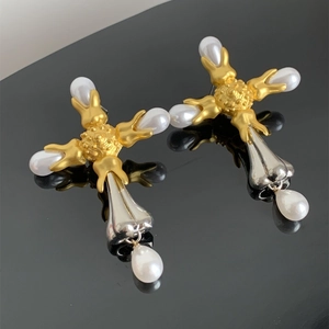 Detailed view of vintage cross earrings with mixed metal finish and hanging pearls