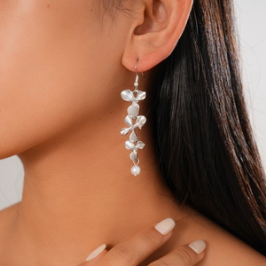 Silver flower drop earring with white faux pearl shown on model in detailed close-up