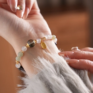 Macro shot of retro beaded bracelet with green crystal beads and golden Fu character charm