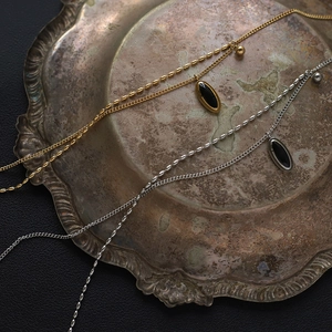 Détail de colliers vintage français avec pendentif ovale noir en finitions or et argent