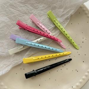Set of eight colorful seamless hair clips with perforated design in a ceramic tray