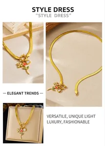 Détail du collier chaîne serpent dorée avec rose en émail rouge et pendentifs trèfle