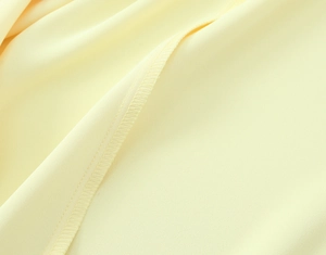 Detailed close-up of pale yellow midi dress fabric showing plain weave and edge stitching
