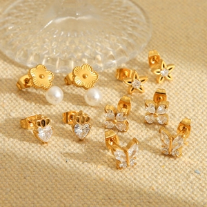Macro shot of gold-plated stainless steel stud earrings with pearls and zircon stones