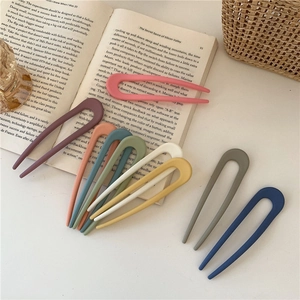 Flat lay of colorful matte U-shaped hairpins on a book with soft natural lighting