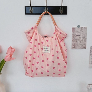 Detail of pink heart canvas tote with woven handles and button closure on hook