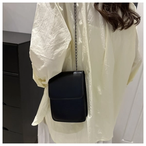 Chic black crossbody mini square bag with metal chain strap shown on a model