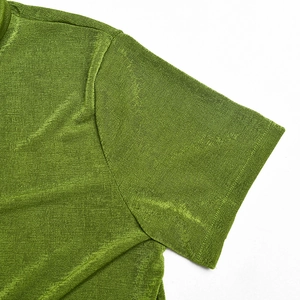 Nahaufnahme des grünen Kurzarmshirts mit feiner Stricktextur und Glanzeffekt