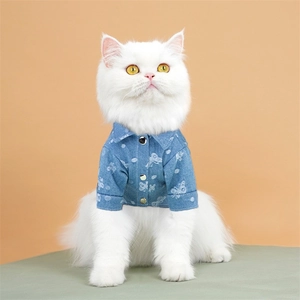 Blue denim pet shirt with white butterfly patterns and metal buttons on a white cat