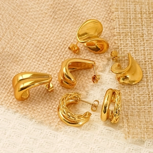 Golden chunky hoop earrings with smooth and twisted metal textures on beige linen fabric